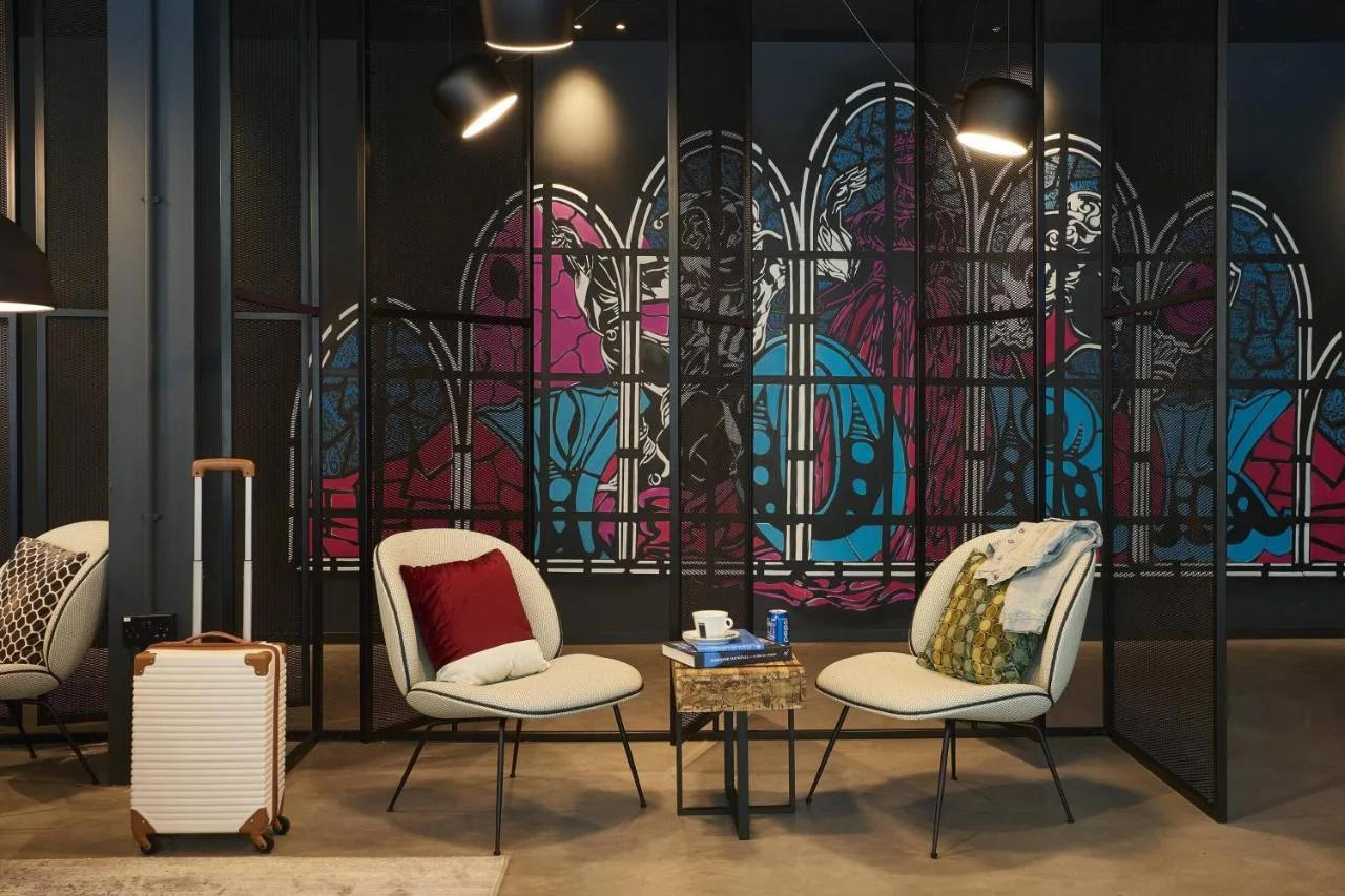 A room with three chairs and a colourful wall at Moxy York in York city centre